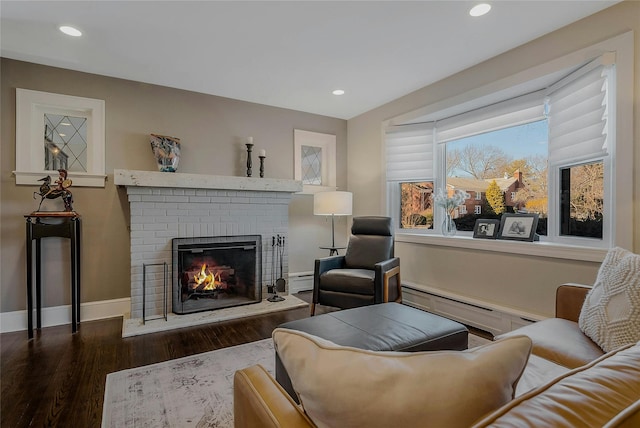 living area featuring recessed lighting, a baseboard heating unit, wood finished floors, baseboards, and a brick fireplace