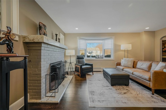 living room with a brick fireplace, arched walkways, dark wood-style flooring, and recessed lighting