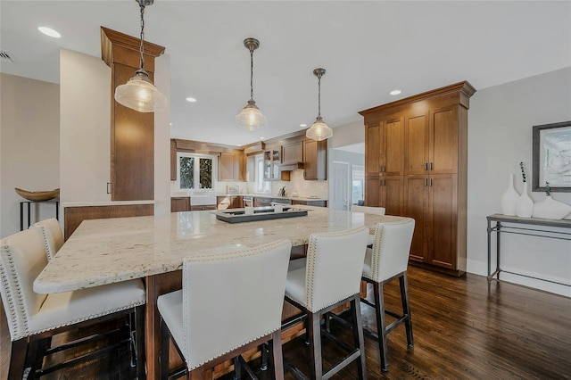 kitchen featuring dark wood-type flooring, recessed lighting, a breakfast bar area, and light stone countertops