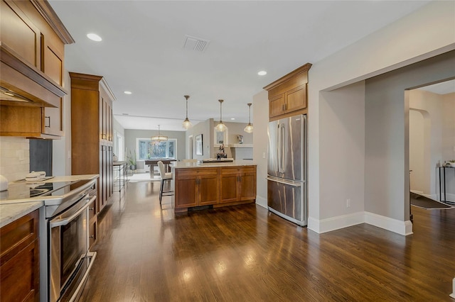 kitchen featuring a peninsula, brown cabinetry, visible vents, and stainless steel appliances