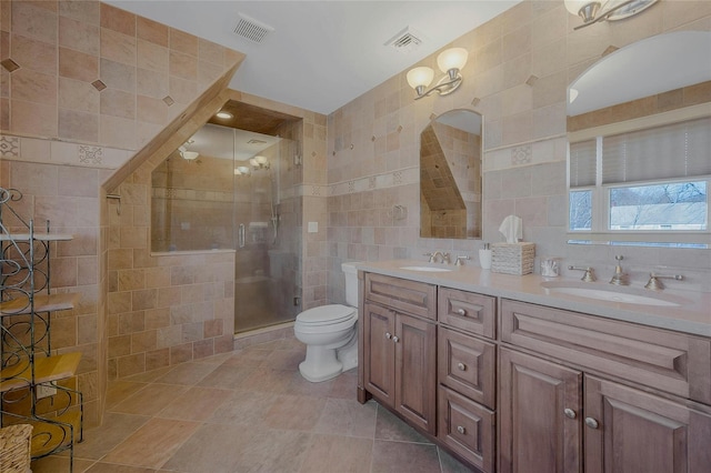 bathroom with visible vents, a sink, tile walls, and a shower stall