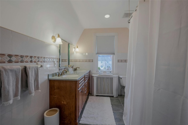 bathroom featuring tile walls, toilet, radiator heating unit, a sink, and tile patterned floors