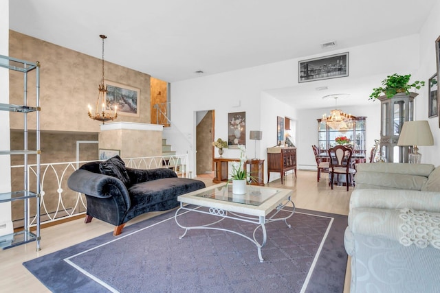 living room featuring visible vents, a notable chandelier, stairway, and wood finished floors