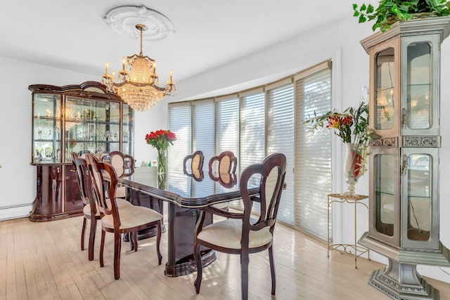 dining area with light wood-type flooring and a notable chandelier