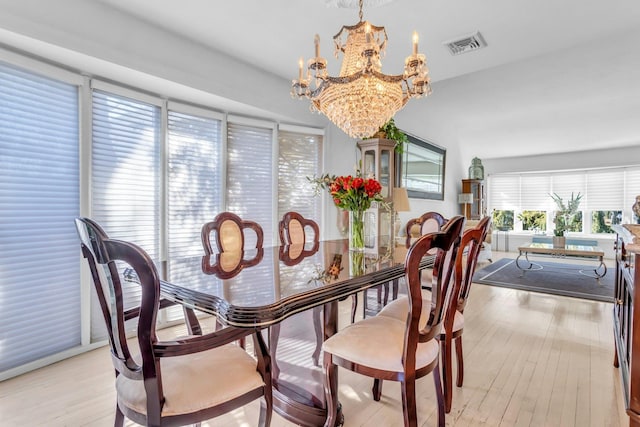 dining space featuring an inviting chandelier, light wood-style flooring, and visible vents