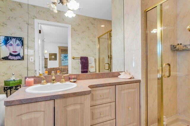 bathroom with a shower stall, vanity, and wallpapered walls