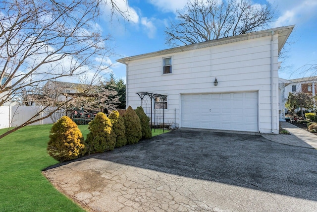 view of home's exterior with a garage, driveway, fence, and a lawn