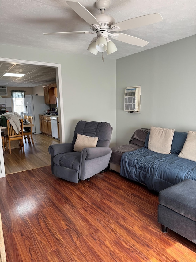 living area featuring a ceiling fan, a wall unit AC, and wood finished floors