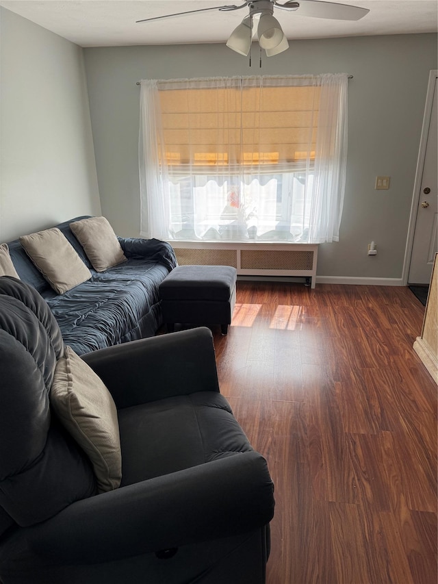 living area featuring dark wood finished floors, a ceiling fan, and baseboards