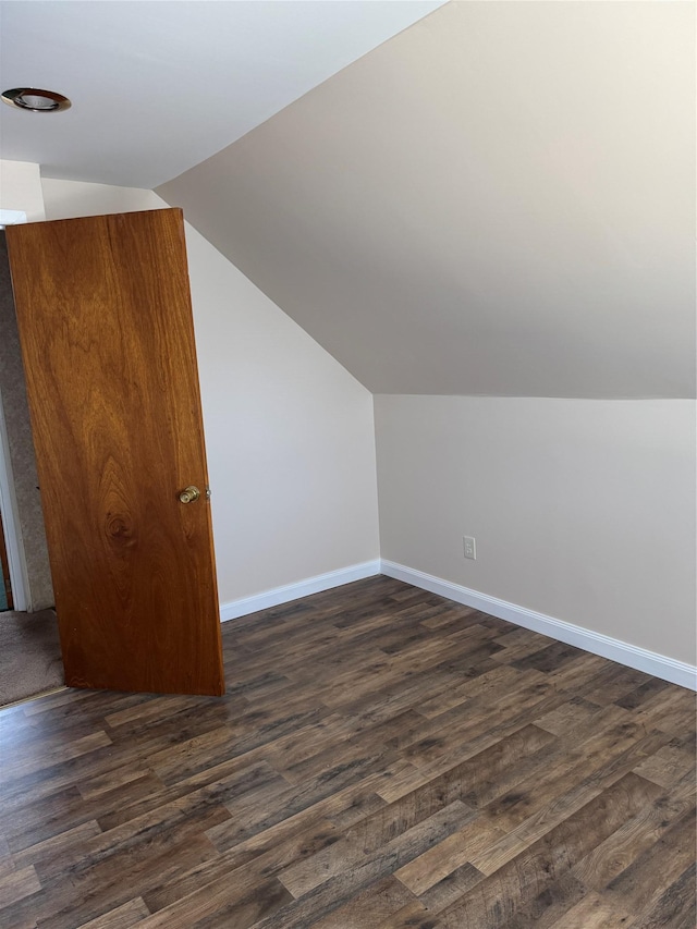 additional living space with lofted ceiling, dark wood finished floors, and baseboards