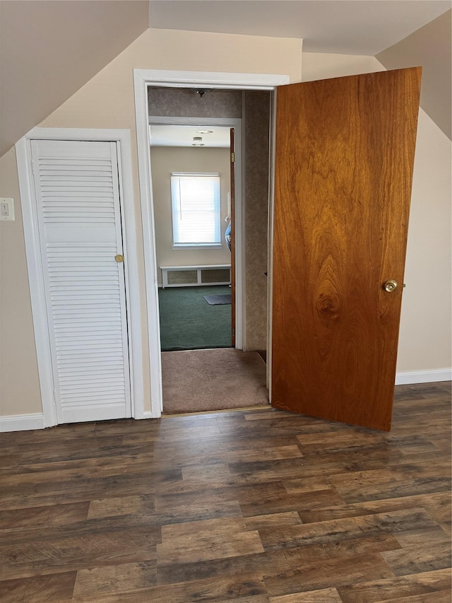 hallway featuring vaulted ceiling, baseboards, and dark wood finished floors