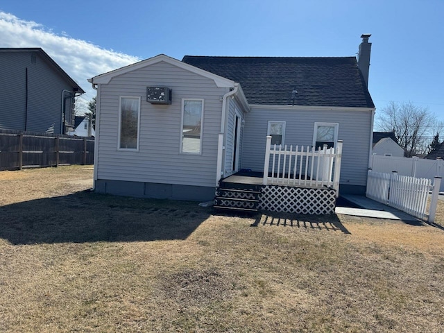 back of house featuring a lawn, a wooden deck, and a fenced backyard