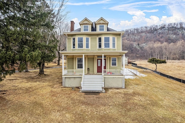 view of front facade with covered porch, a chimney, fence, and stairs