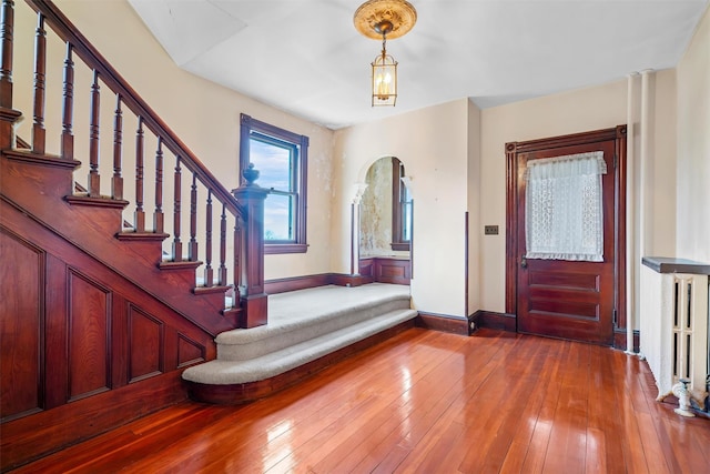 foyer entrance with arched walkways, stairway, hardwood / wood-style flooring, and baseboards