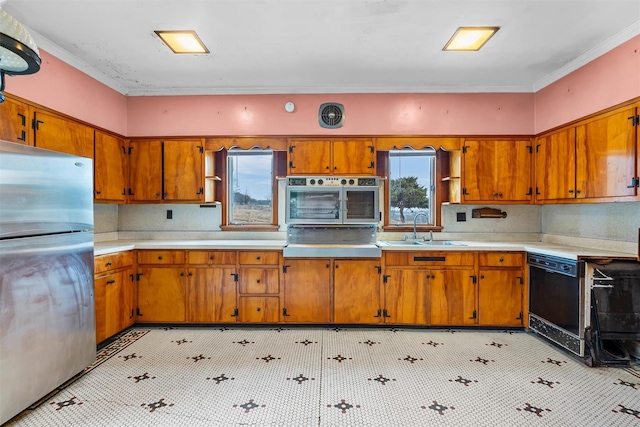 kitchen featuring brown cabinets, freestanding refrigerator, a sink, oven, and dishwasher