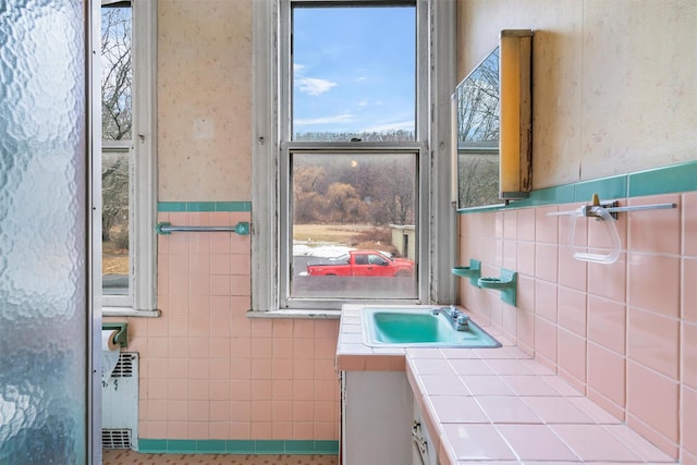 bathroom featuring a wainscoted wall, vanity, tile walls, radiator, and wallpapered walls