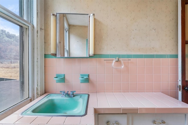 bathroom with wainscoting, a sink, and wallpapered walls