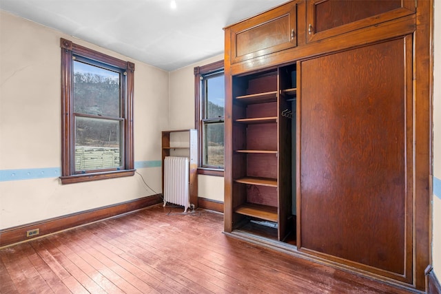 interior space with radiator, baseboards, and hardwood / wood-style floors