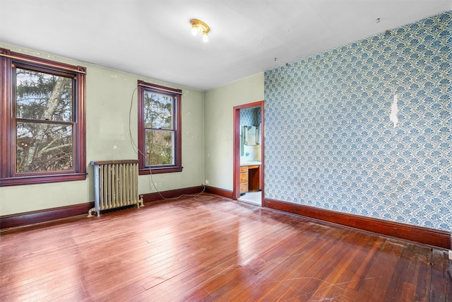 spare room featuring baseboards, radiator heating unit, and hardwood / wood-style flooring