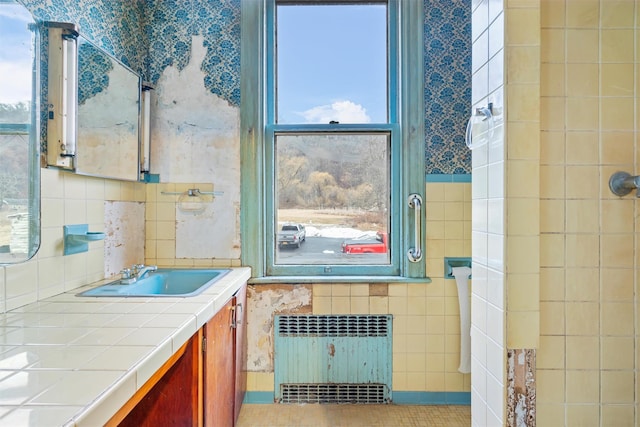 bathroom with radiator, tile patterned flooring, tile walls, and vanity