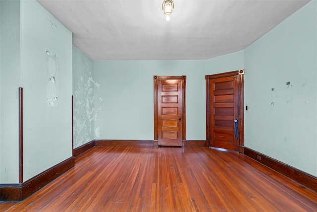 spare room featuring hardwood / wood-style flooring and baseboards