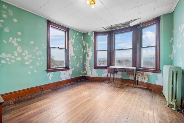 empty room featuring radiator, baseboards, and hardwood / wood-style floors