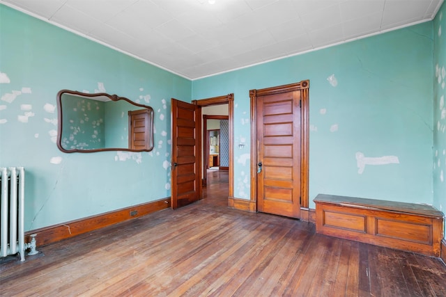 spare room with radiator, wood-type flooring, and baseboards