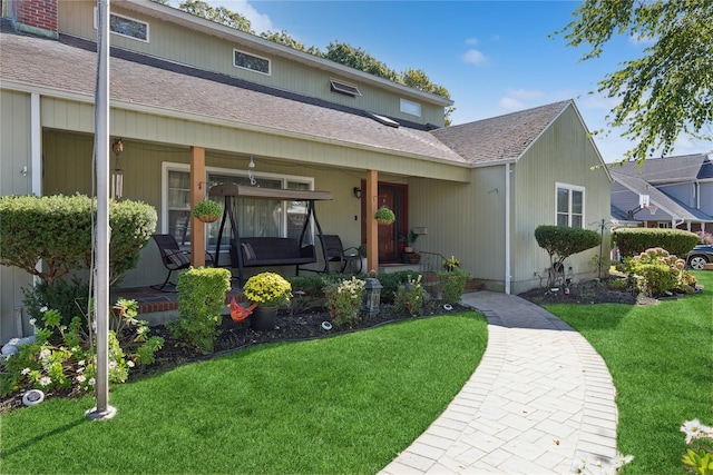 view of front of house with covered porch, a shingled roof, and a front lawn