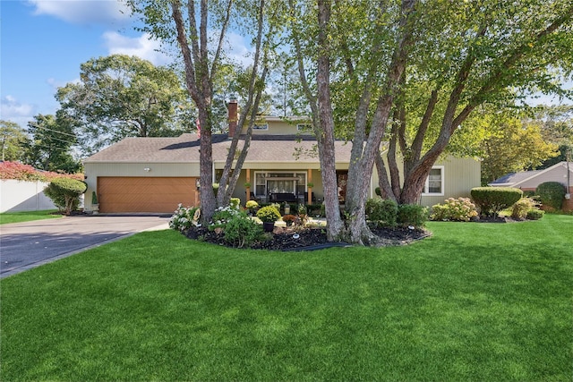 view of front facade featuring a garage, solar panels, fence, concrete driveway, and a front lawn