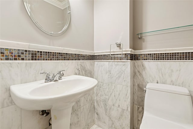 bathroom featuring a wainscoted wall, a sink, tile walls, and toilet