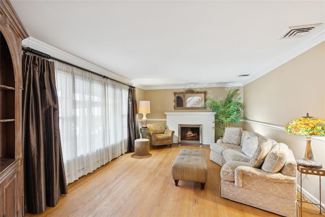 living room with visible vents, crown molding, a lit fireplace, and light wood finished floors