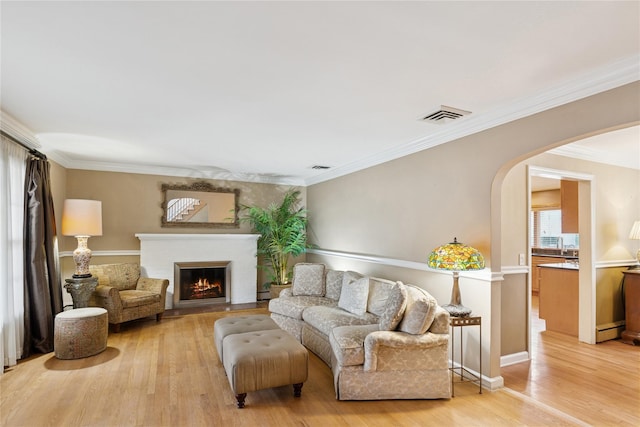 living area with light wood-style flooring, visible vents, arched walkways, and ornamental molding