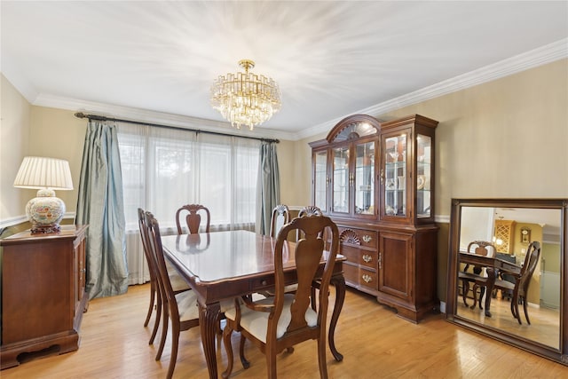 dining area with a chandelier, crown molding, and light wood-style floors