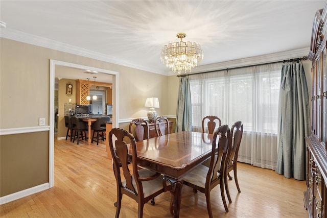 dining room with a chandelier, light wood finished floors, baseboards, and crown molding