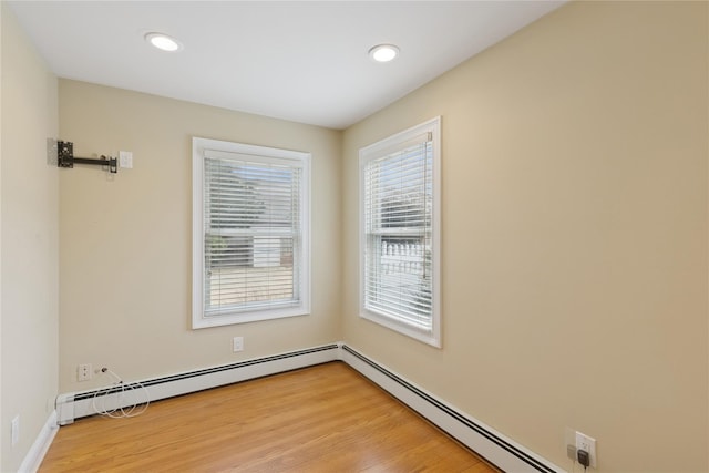 unfurnished room with light wood-type flooring, a baseboard radiator, and recessed lighting