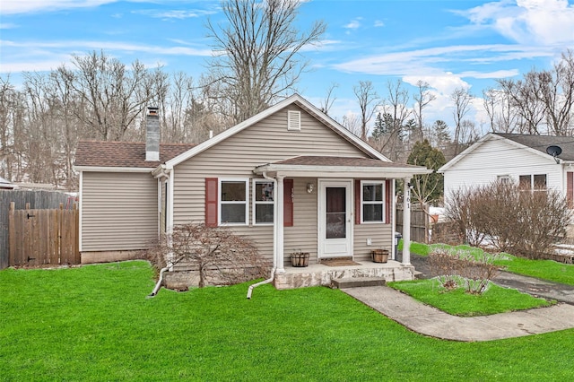 view of front of property featuring a shingled roof, a front yard, fence, and a chimney