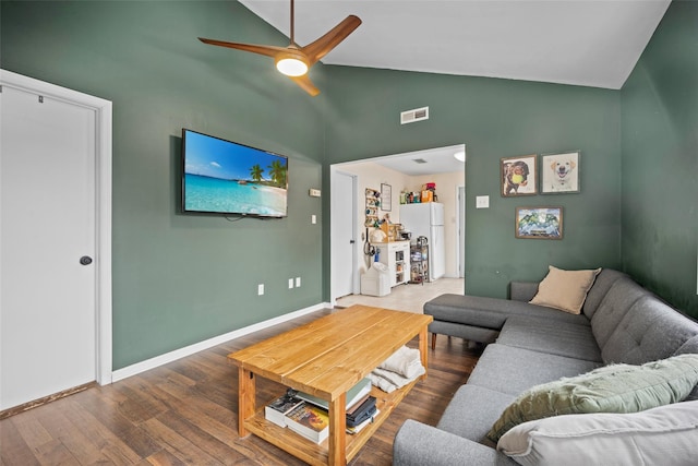 living area with lofted ceiling, wood finished floors, a ceiling fan, visible vents, and baseboards