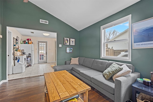 living area with visible vents, vaulted ceiling, and wood finished floors