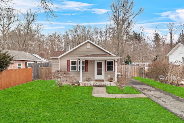 bungalow-style home featuring a front lawn, a chimney, fence, and aphalt driveway