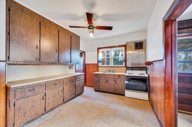 kitchen featuring light countertops, a wainscoted wall, a sink, and white electric range oven