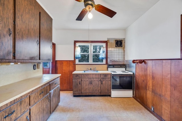 kitchen featuring a wainscoted wall, electric range, wood walls, visible vents, and light countertops