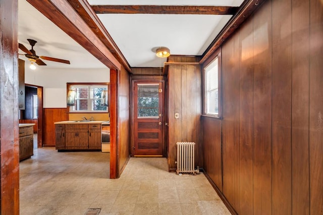 interior space with a wealth of natural light, radiator, wood walls, and beam ceiling