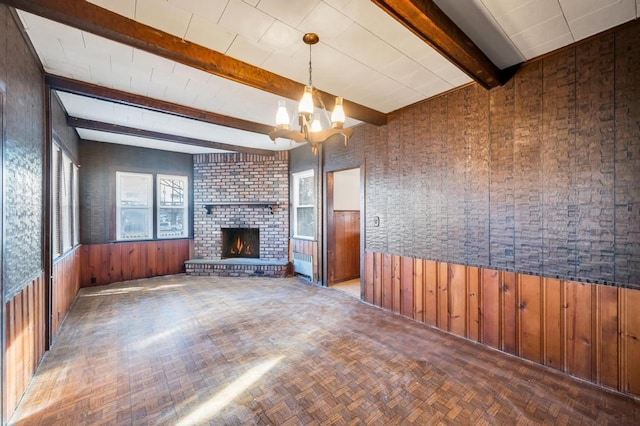 unfurnished living room featuring a wainscoted wall, beamed ceiling, wood walls, and a fireplace