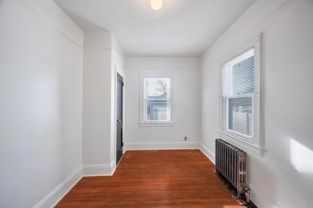 unfurnished room featuring radiator, baseboards, and wood finished floors