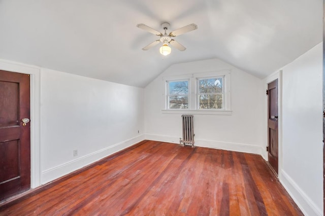 additional living space with baseboards, vaulted ceiling, radiator heating unit, and wood finished floors