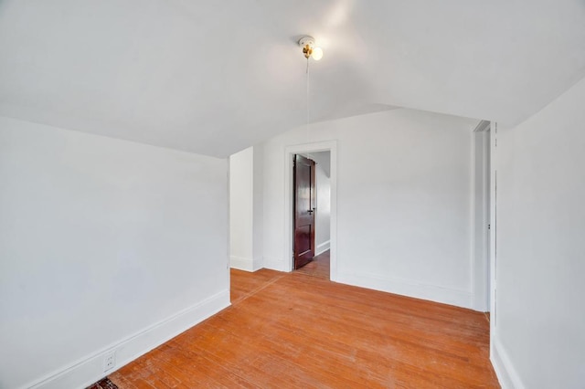 interior space featuring light wood-type flooring, baseboards, and vaulted ceiling