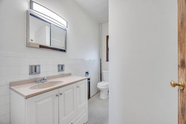 bathroom with wainscoting, toilet, tile walls, and vanity