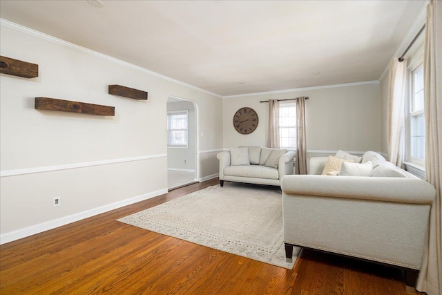 living room featuring baseboards, arched walkways, wood finished floors, and ornamental molding