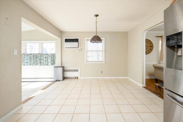 unfurnished dining area with light tile patterned floors, a wall unit AC, a baseboard radiator, and radiator