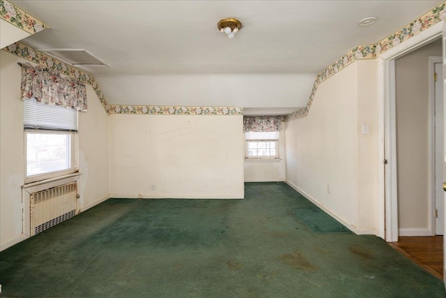 spare room with dark colored carpet, radiator heating unit, attic access, and baseboards